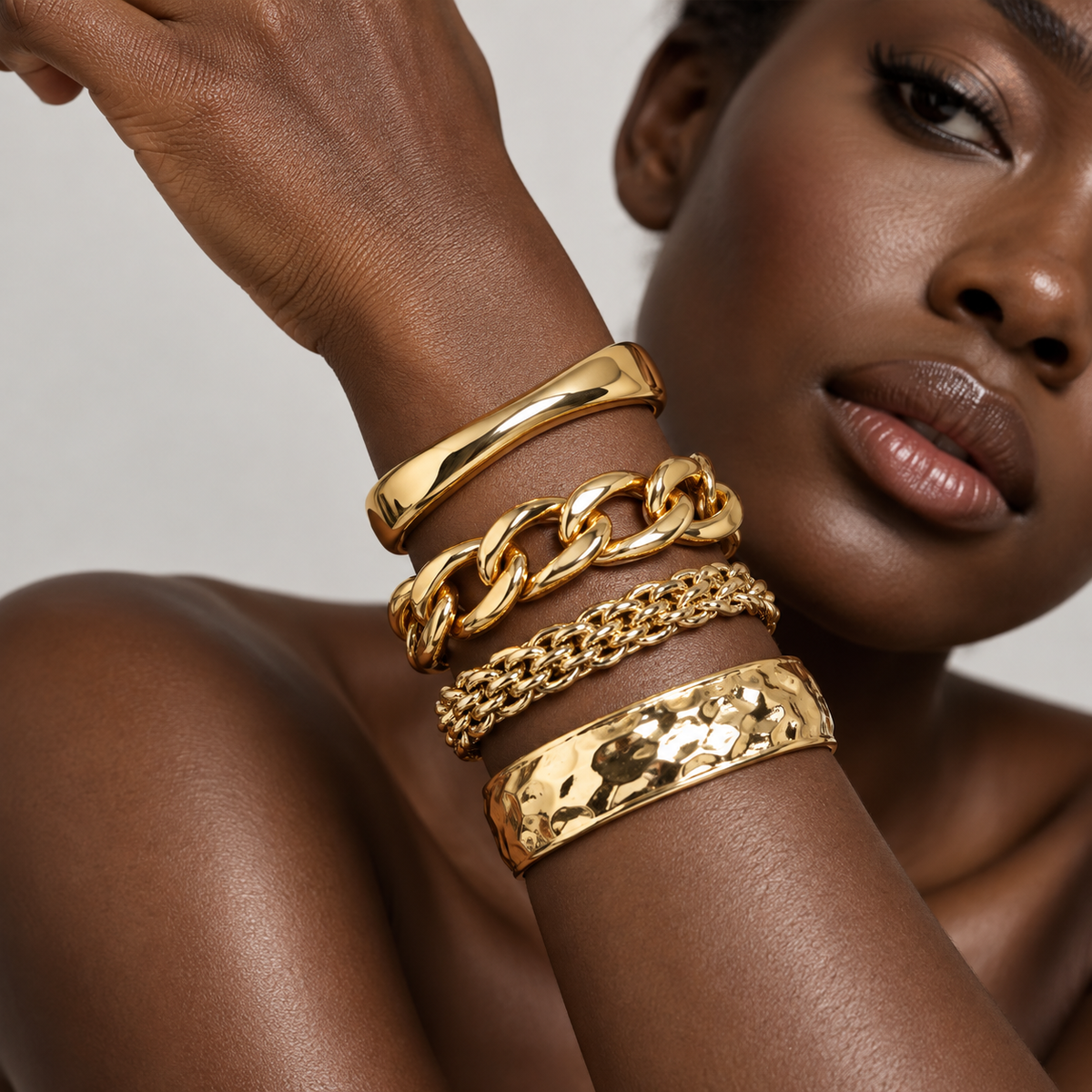 Deep dark-skinned Black model showcasing layered gold bracelets on bare skin